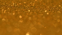 Glittering Golden Particles With Bokeh. Yellow gold defocused circular facula. Natural Floating Organic Abstract Particles. Background. Christmas and Happy new year. Slow motion.