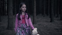 girl alone in the woods with a teddy bear 