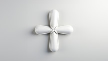A modern small cross in white ceramic material. Set against a white studio background,