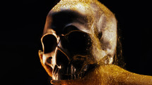 Golden female hand with human skull on black background. Mystique, ancient history concept. Power of symbolism - mortality and rebellion. Exploring life, death, gothic aesthetics. Dramatic metaphor.