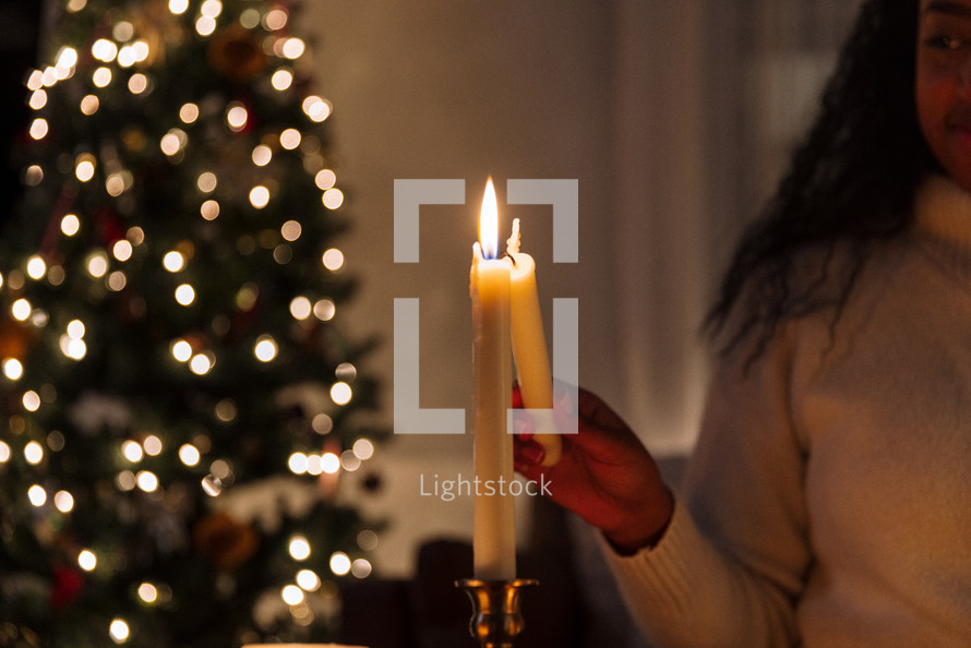 Woman lighting a taper candle.