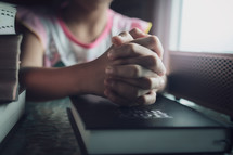 Hands of a girl praying with the BIble