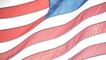 close-up of waving bright american flag illuminated from behind