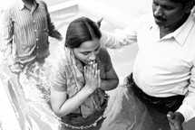 woman in prayer about to be dunked during a baptism