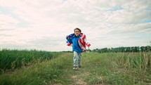 Cute little boy - American patriot kid running with national flag on open area countryside road.USA, 4th of July - Independence day, celebration. US banner, memorial Veterans, election, America, labor