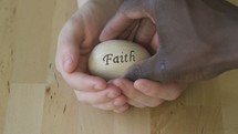 cupped hands holding an egg with the word faith 