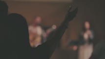 woman with hands raised during a worship service listening to worship music 