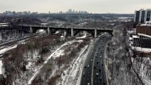 Aerial orbit drone shot of Prince Edward Viaduct Toronto eastside neighborhood on a cold winter day. Moderate vehicular traffic. Aircraft is flying right above Don River and Don Valley Parkway. 