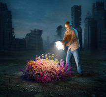 A man holds out a book to reveal bright flowers in a desolate landscape.