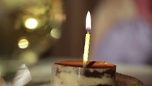 Glass of champagne and candle in the tiramisu cake