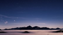 Blue starry sky with stars motion in misty mountains, foggy clouds in Nature Astronomy Time lapse
