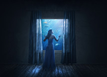 woman looking out a window into an aquarium 