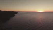 drone over ocean and shoreline at sunset 