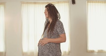 Pregnant woman soft smiling while holding her belly.