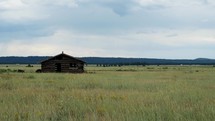 An old log cabin on a vast prairie