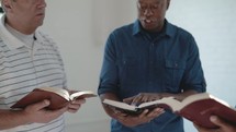 a group of men reading Bibles and discussing scripture 