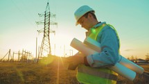 Industry energy business concept. Silhouette electrical engineer a working near tower with electricity at sunset time. Electrical worker inspect voltage electricity pylon. Power generation industry.