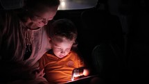 Little boy using tablet pc during car travel at night
