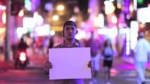 Man holding a blank sign in a red light district street