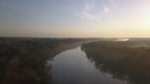 Aerial over a misty river winding through the trees