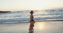 Slow motion of Mother and young girl running on the beach during sunset