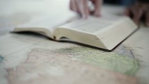 a person reading a Bible on a world map 