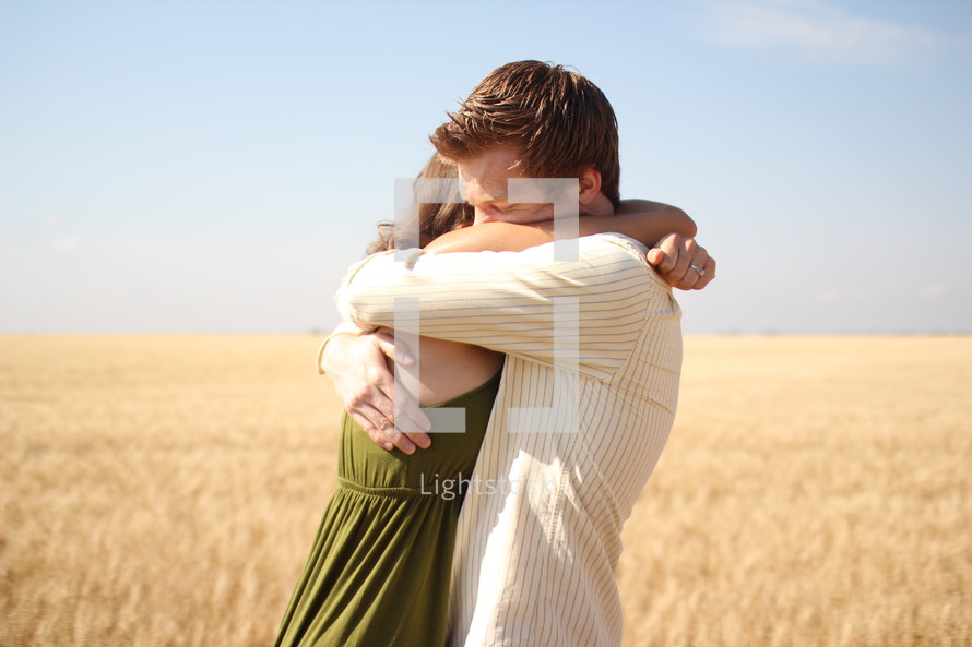 a couple hugging in a field 