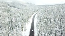 aerial view over a snowy forest and highway 