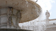 Old fountain, statue of Monk. Slow motion. Architecture and landmark of Vatican. Water drops splashing and dripping on fountain surface in old european city.