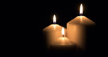 Three white candles burning on black background. 4k