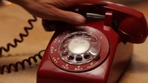A woman frantically dialing 911 on a vintage rotary phone