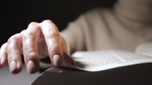 Close up of a woman's hand as she flips pages in a Bible.
