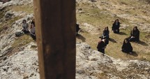 people kneeling in prayer on a mountaintop behind a cross 