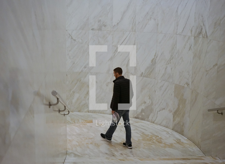 a man walking through a marble hallway 