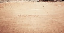 Word honey moon written in sand 
