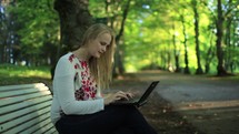 Young woman using her laptop in the park