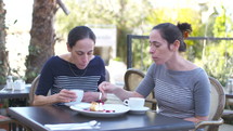 Two Caucasian female identical twins sitting together at a cafe