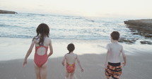 Three kids running and playing on the beach