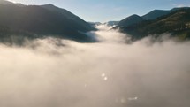 Aerial view of foggy clouds in alpine mountains valley of autumn nature
