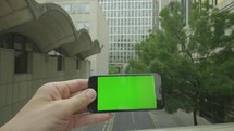 Personal perspective of a businessman using a smartphone with a green screen