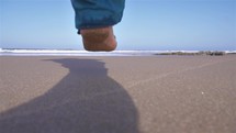 Slow motion of man running barefoot on the beach in sunny morning nature, active outdoor travel

