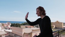 Woman Dressed In Black Greets Her Neighbors From The Balcony