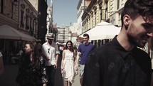people walking on a cobblestone street between shops 