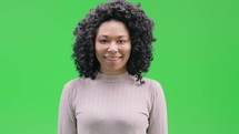 Woman on green screen smiling and holding up an OK sign