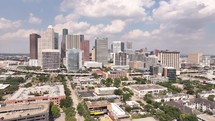 Aerial video of downtown Houston, Texas on a beautiful blue sky cloudy day with tall buildings in the background.