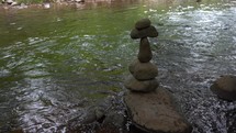 A rock cairn stacked in a peaceful mountain stream
