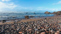 Rocky ocean coast with round pebble rocks and slow motion waves, Travel Morocco background

