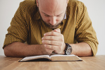 man with his head bowed reading a BIble
