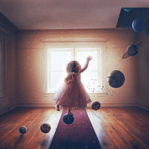 A little girl steps on the planets of the solar system