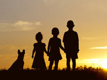 silhouettes of kids and their dog at sunset 